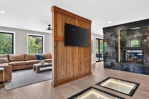 Ein modernes Wohnzimmer mit einer Wand aus Holzpaneelen, einem Flachbildfernseher, einem Kamin und einem Sofa.
