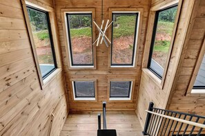 Eine Holzhütte mit Holzinnenraum, mehreren Fenstern und einem zentralen Holzbalkenbau.