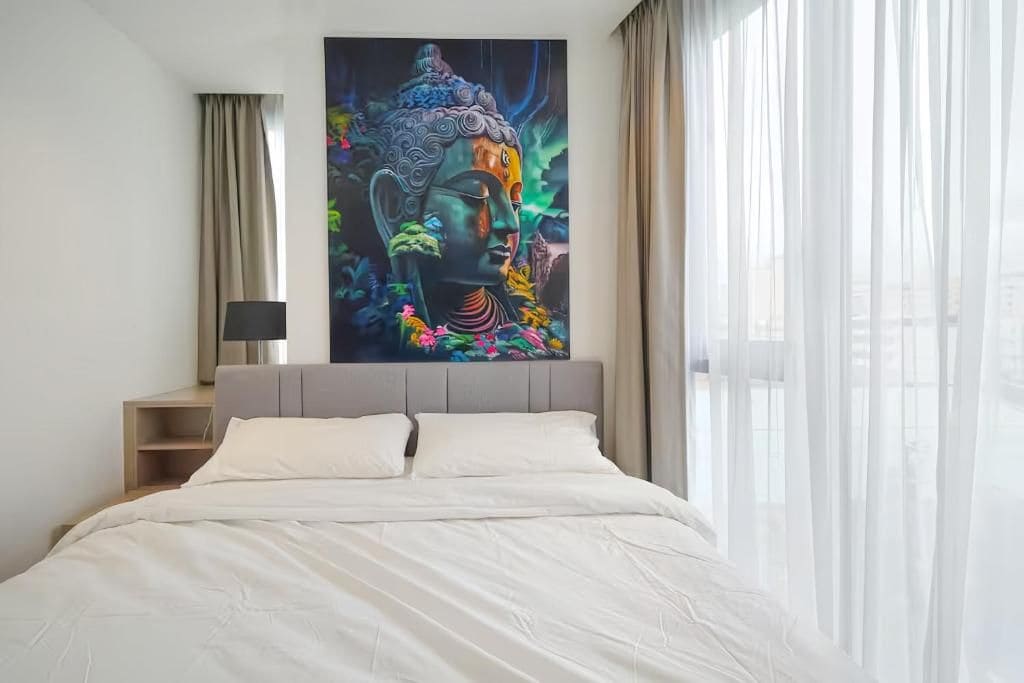 A bedroom with a bed, a nightstand, a lamp, and a large painting on the wall.