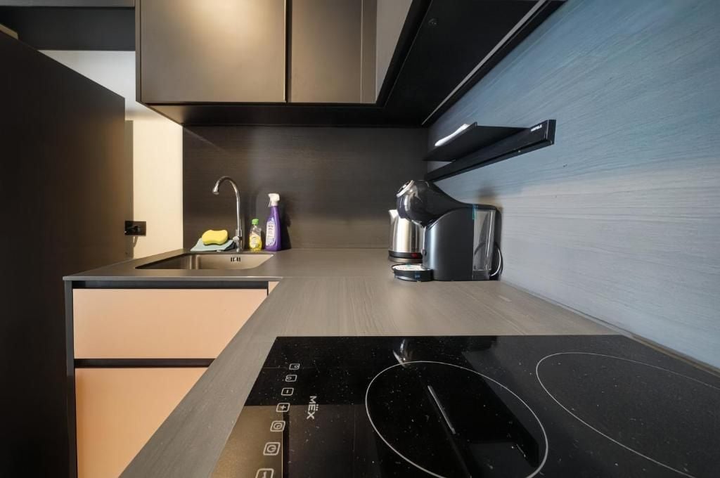 A modern kitchen with a built-in induction cooktop, a stainless steel sink, and a kettle.