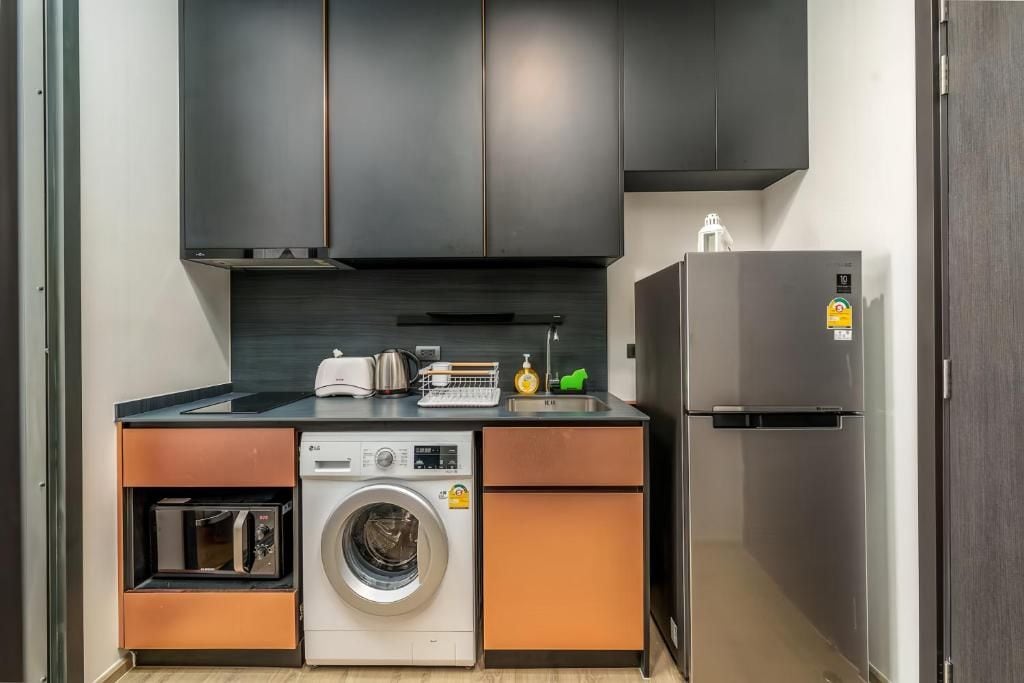 A compact kitchen with a washing machine, a built-in oven, and a refrigerator.