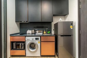 A compact kitchen with a washing machine, a built-in oven, and a refrigerator. - Edge Central Pattaya (Pattaya City)