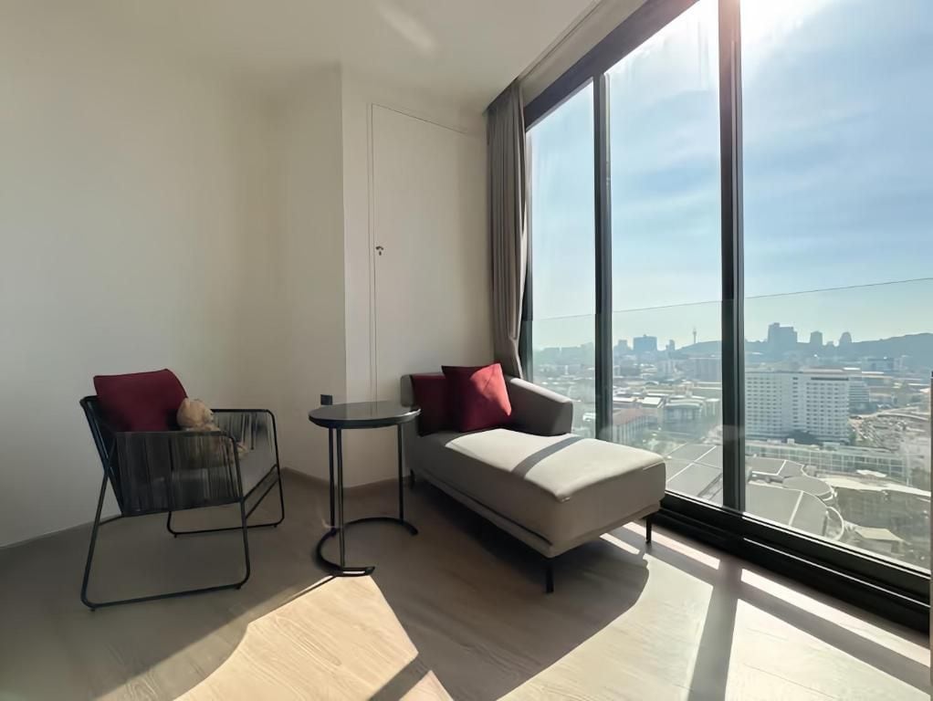 A modern room with a large window, a sofa, a chair, and a small table.