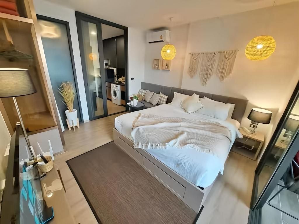 A modern bedroom with a large bed, bedside tables, a wardrobe, and a washing machine.