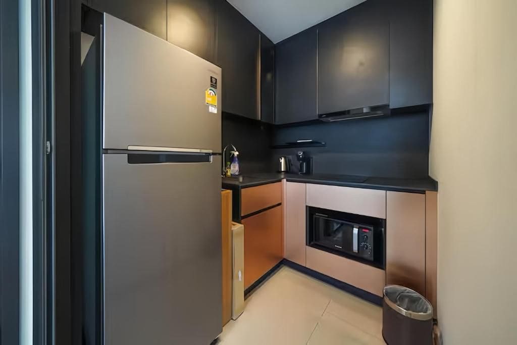 A compact kitchen with a built-in oven, a refrigerator, and a microwave.