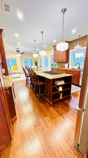 Una cocina amplia con una isla central, armarios de madera e iluminación colgante.