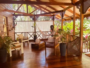 A wooden deck with a hammock, chairs, and potted plants. - Casa Caribeña (Limón)