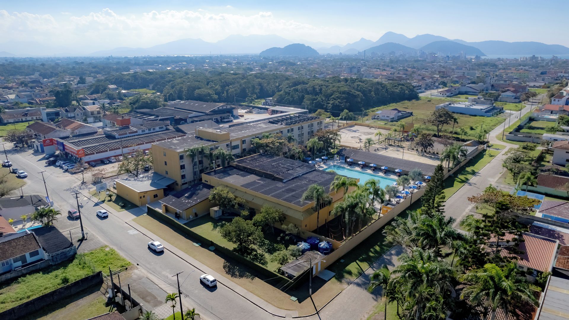 Um hotel com piscina, rodeado por vegetação e vista para montanhas distantes.