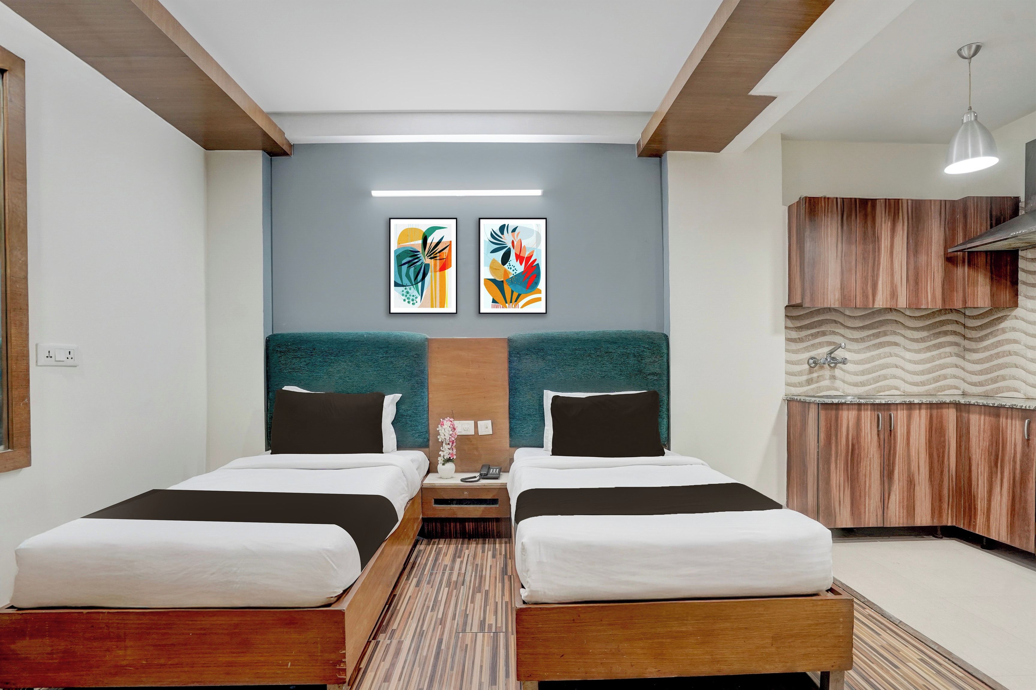 A hotel room with two beds, a small table, a nightstand, a wall-mounted telephone, and a decorative wall panel.