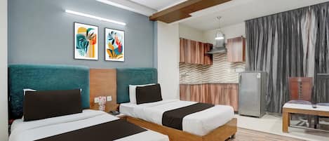 A hotel room with two beds, a kitchenette, and a bathroom.