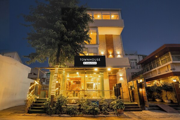A modern townhouse with a well-lit entrance, a visible staircase, and a sign indicating it is company-serviced.