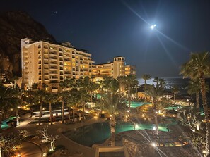 Ein Resort mit mehreren Schwimmbecken, Palmen und einem großen Gebäude mit Balkonen.