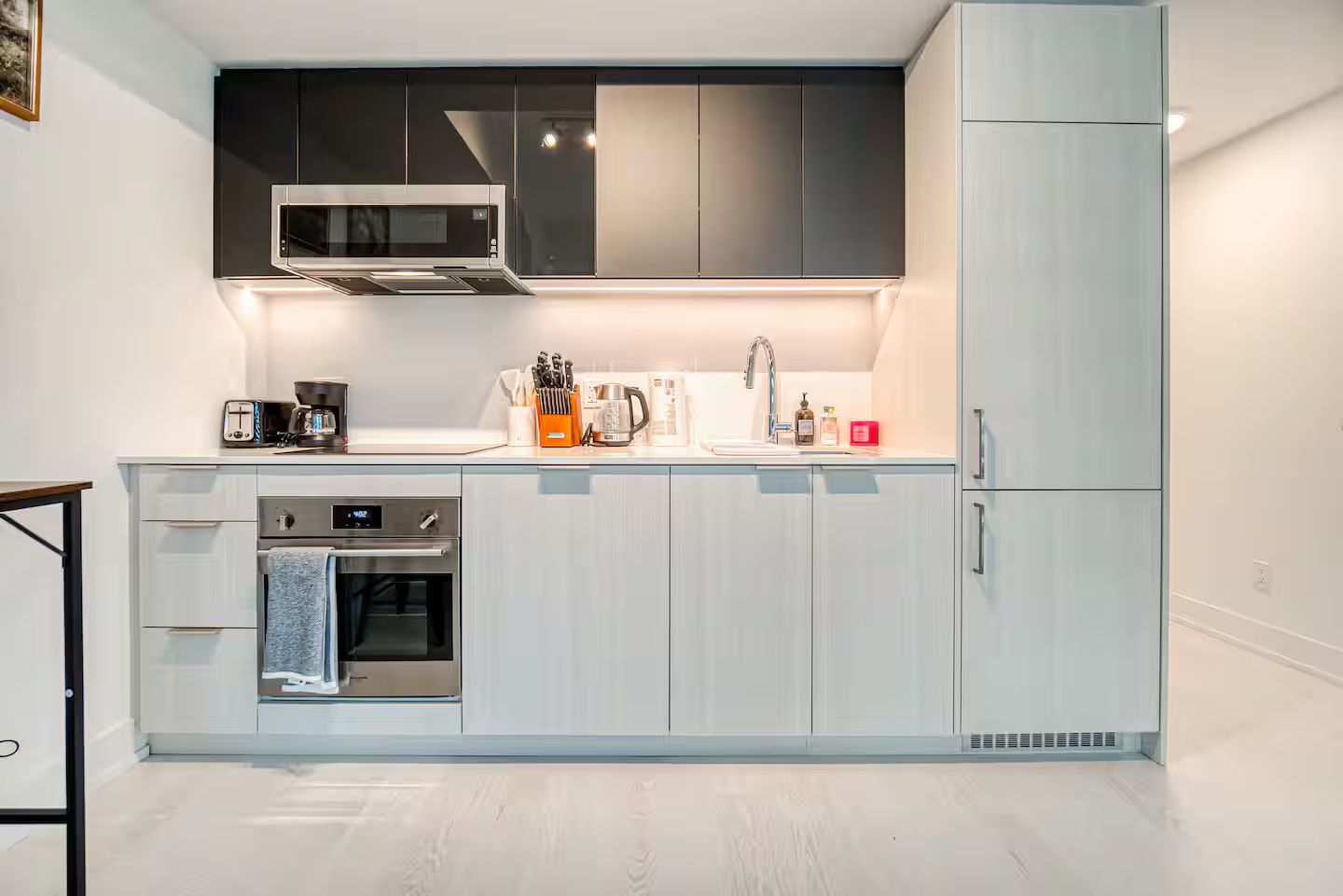 Uma cozinha moderna com micro-ondas, forno e pia embutidos, armários em tons claros e design minimalista.