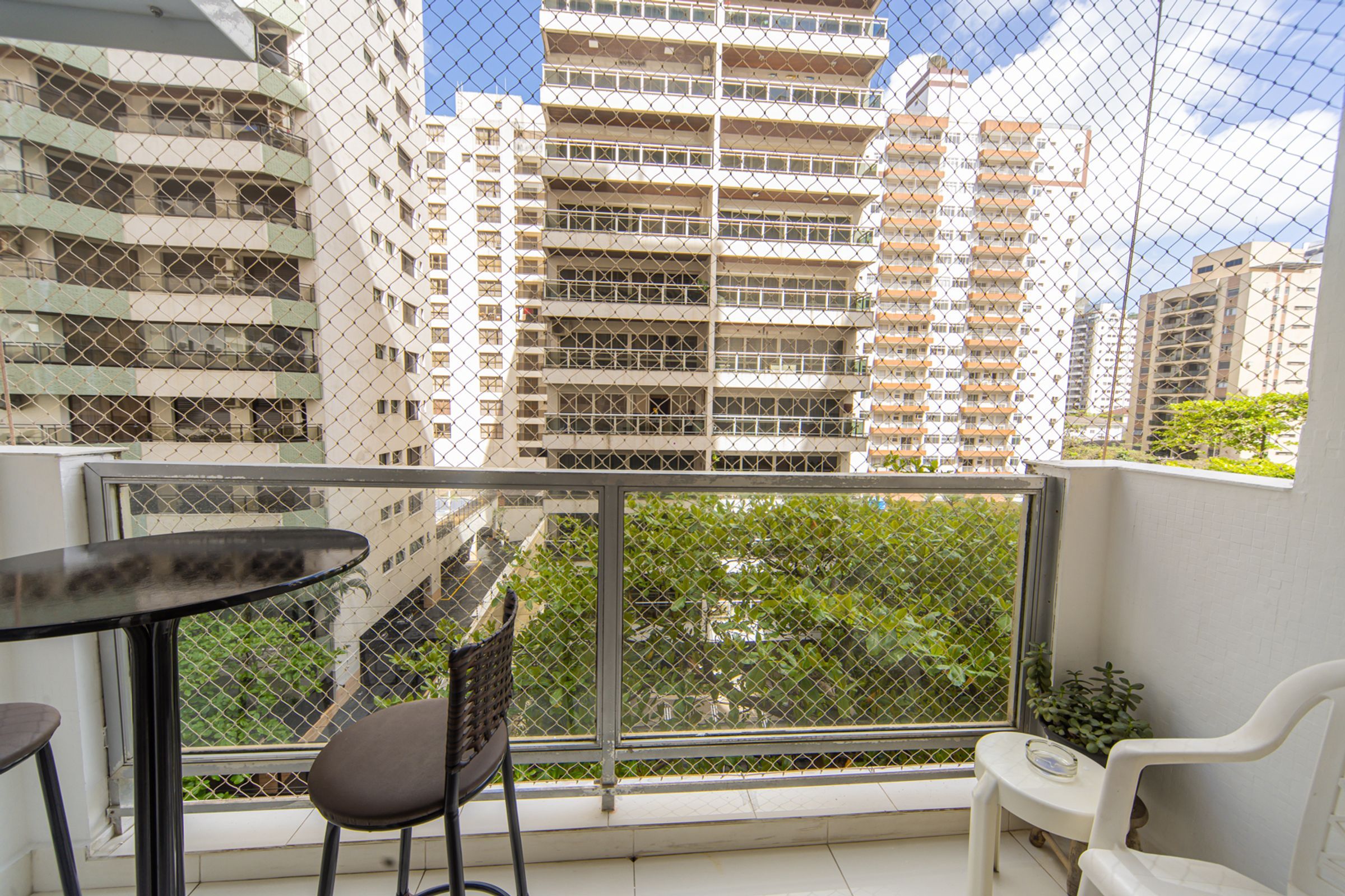Un balcón con mesa y sillas, con vista a un paisaje urbano de edificios altos.