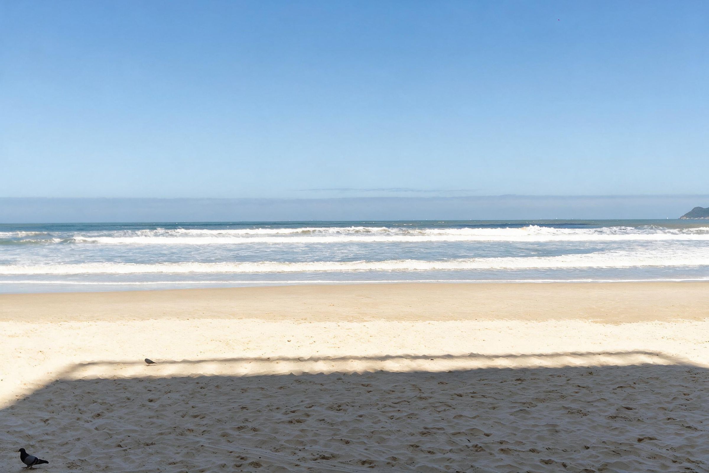 Ein Strand mit klarem Himmel und Wellen.