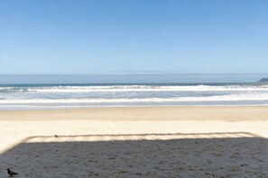A beach with a clear sky and waves. - Apt for 5 w/ AC 150m from Pitangueiras Beach (Guarujá)