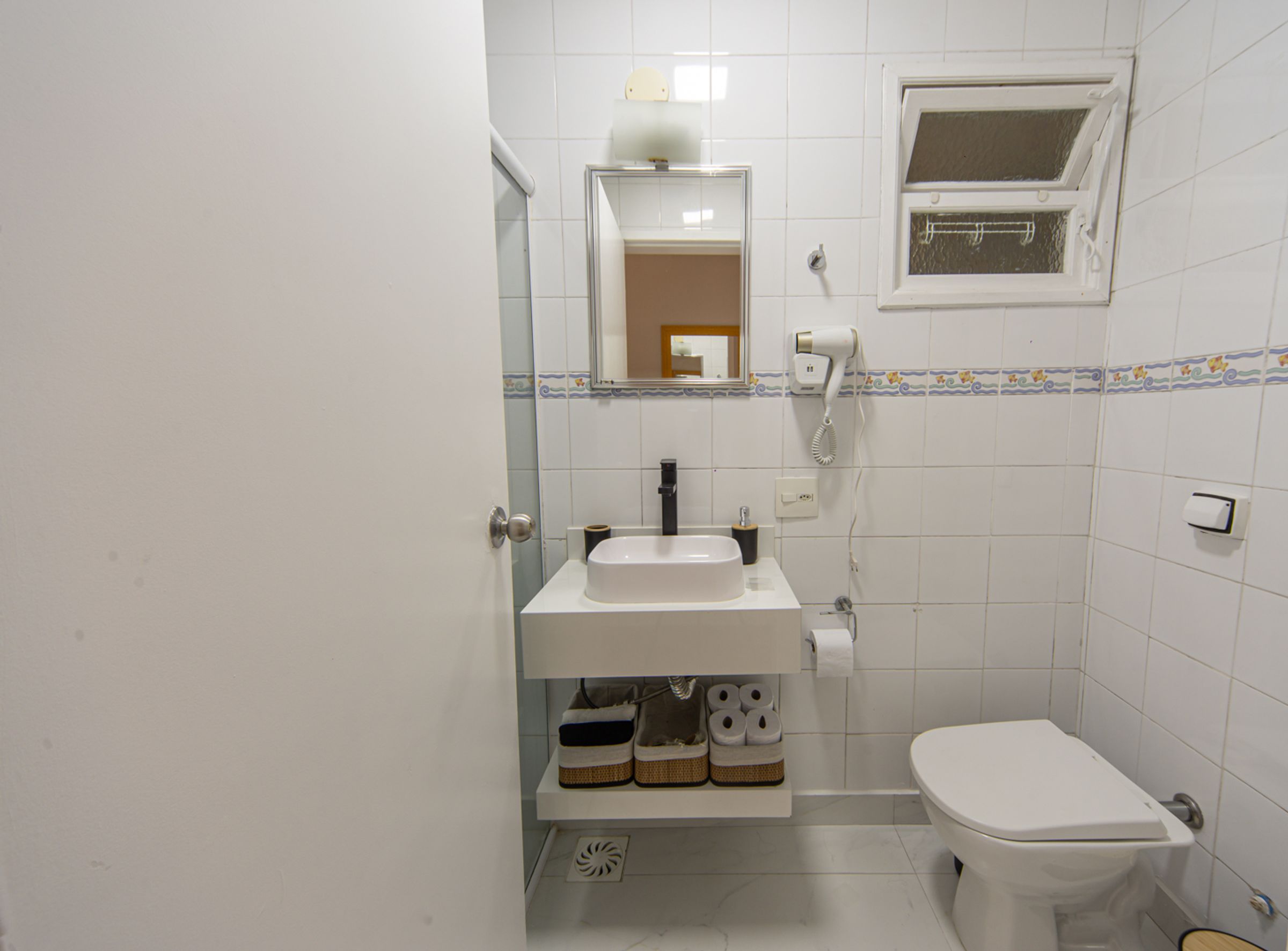 A bathroom with a white sink, toilet, and a mirror above the sink.