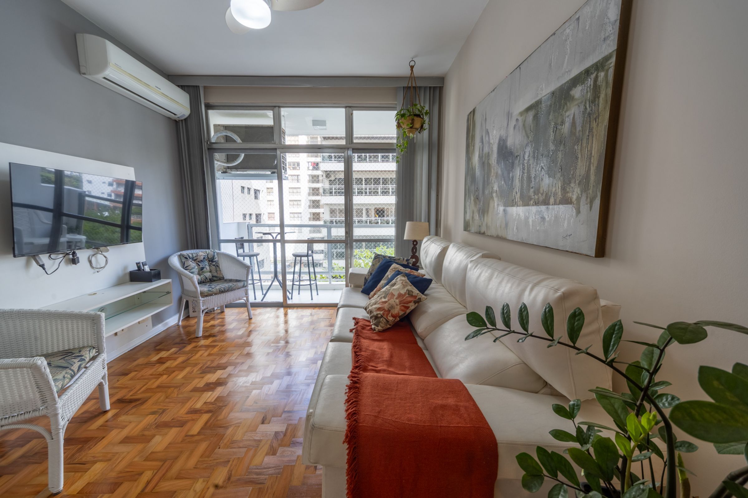 Una sala moderna con un sofá, una televisión, un sillón y un ventanal grande.