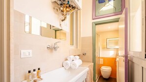A bathroom with a white sink, two mirrors, a towel rack with towels, and a toilet visible through an open door. - Mediterra Spacious Apartment | Stylish 3BR in Bari (Bari)