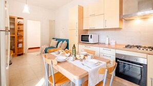 A modern kitchen with a dining table set for two, a microwave, oven, and a built-in stove. - Mediterra Spacious Apartment | Stylish 3BR in Bari (Bari)