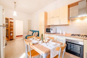 Una cucina moderna con un tavolo da pranzo apparecchiato per due, un forno a microonde, un forno e un piano cottura integrato.