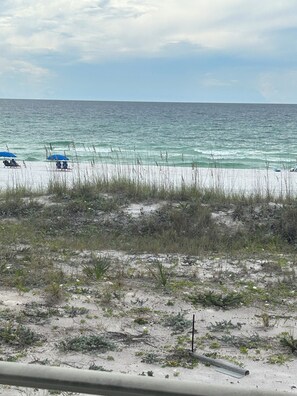 A beach with a sandy shore, some vegetation, and the ocean in the background. - Beautiful 1 bedroom condominium steps away from the sugar white beach! (Fort Walton Beach)
