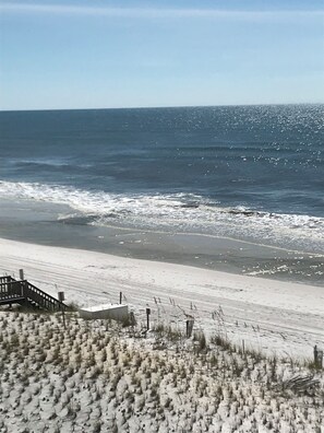 A beach with a wooden walkway leading to a structure, and the ocean in the background. - Beautiful 1 bedroom condominium steps away from the sugar white beach! (Fort Walton Beach)