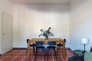 Ein Essbereich mit einem Holztisch, vier Stühlen, einer Zimmerpflanze und einer Lampe.