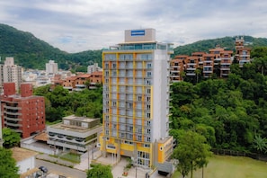 A multi-story building with a modern design, featuring balconies and a prominent sign at the top. - Guarujá By Candeias (Guarujá)