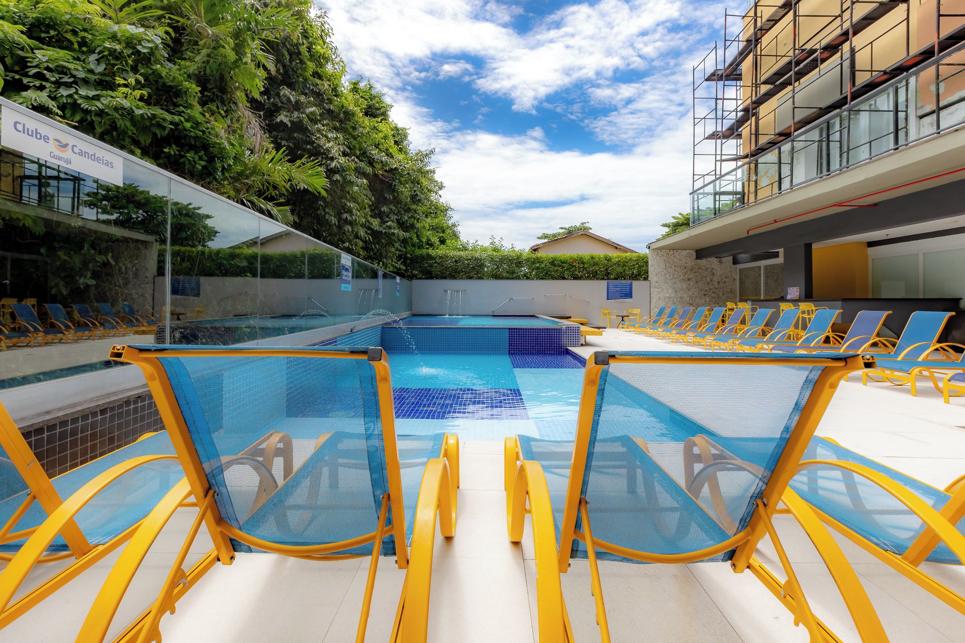 Una piscina con agua azul, rodeada de sillas de descanso amarillas.
