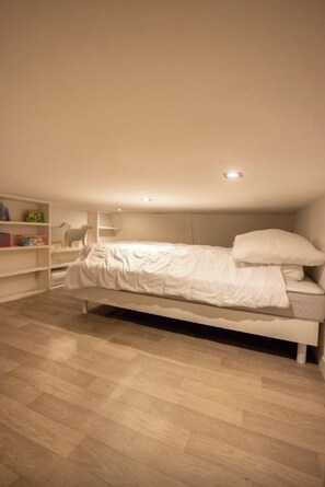 A bedroom with a single bed, a white wardrobe, and a shelf unit. - Apartment, big terrace, pool, walk to sea (Sanary-sur-Mer)