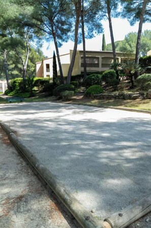 A paved driveway leading to a building with a sloped roof and a beige facade, surrounded by trees and shrubs. - Apartment, big terrace, pool, walk to sea (Sanary-sur-Mer)