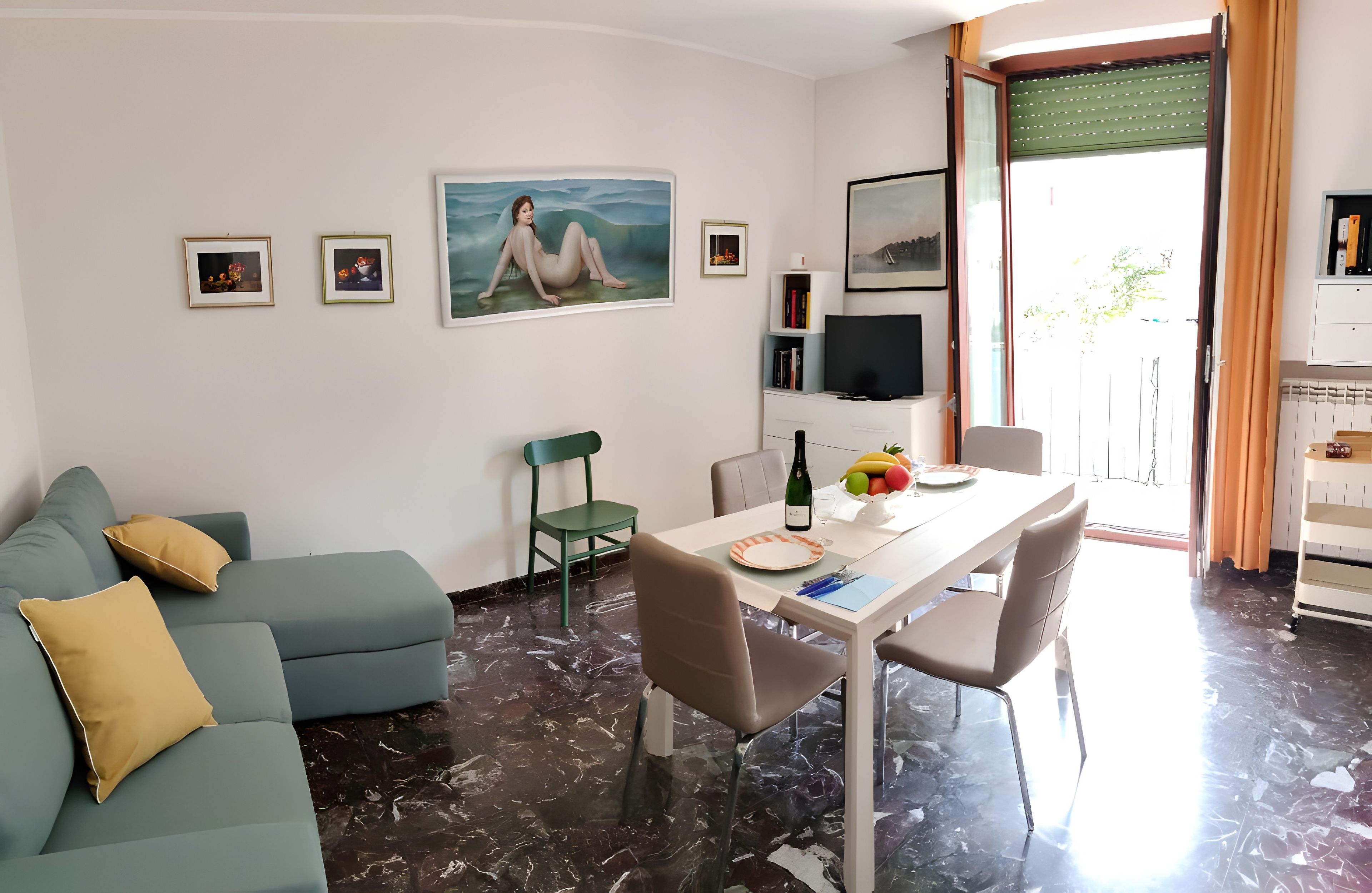 Ein modernes Wohnzimmer mit einer Couch, einem Esstisch mit Stühlen, einem Fernseher und Kunstwerken an den Wänden.