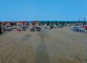 Una spiaggia con numerosi lettini e ombrelloni, cielo sereno e mare calmo.