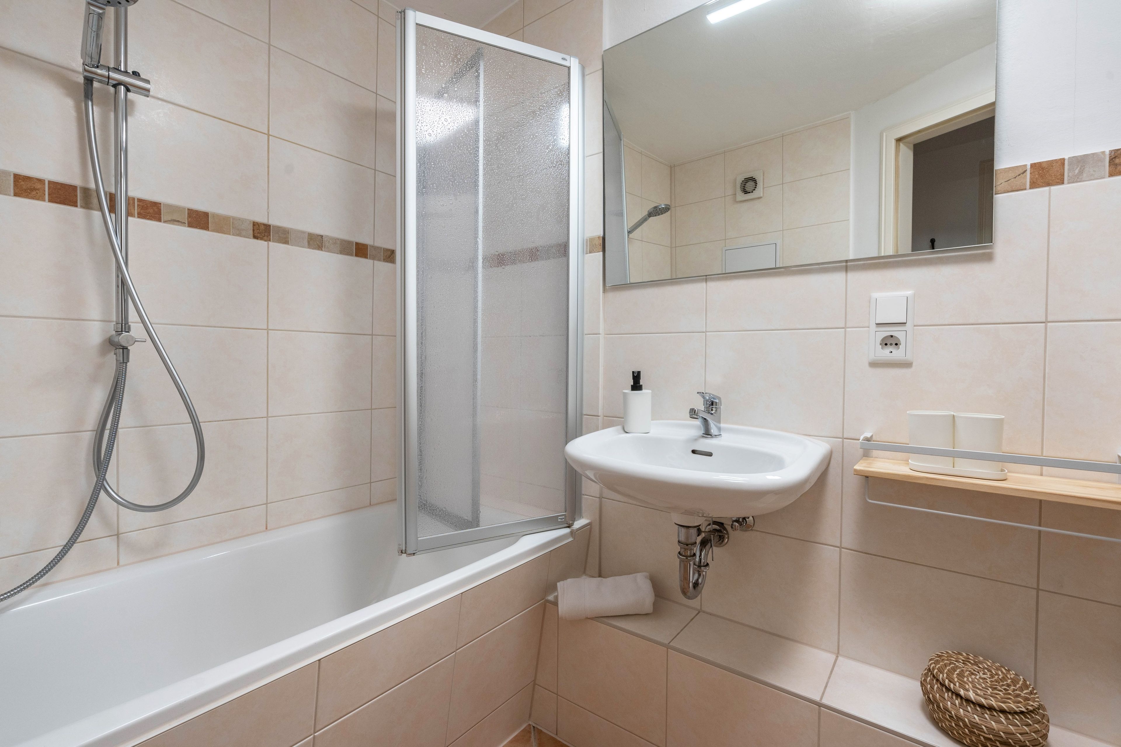 Ein Badezimmer mit einer Badewanne, einer Duschkabine, einem Waschbecken und einem Spiegel.