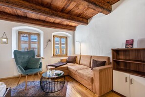 Una sala de estar acogedora con un sillón azul, un sofá color beige y un aparador de madera.