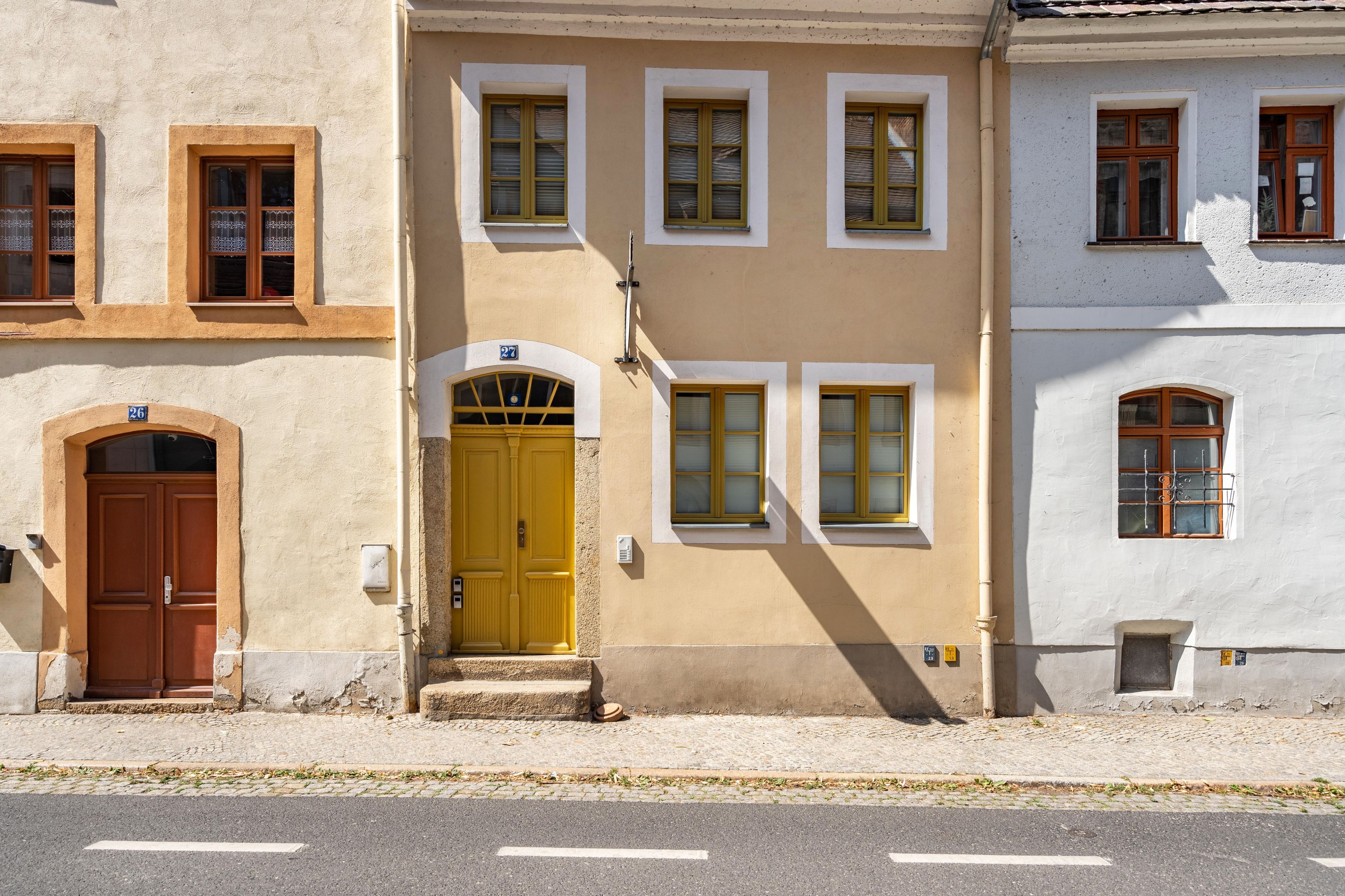 Ein Gebäude mit gelbem Eingang, zahlreichen Fenstern und einer Kopfsteinpflasterstraße.