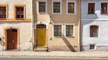Ein Gebäude mit gelbem Eingang, zahlreichen Fenstern und einer Kopfsteinpflasterstraße.