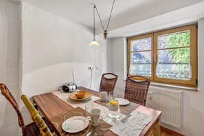 Ein Essbereich mit einem Holztisch, Stühlen, einem Radio und einem Fenster mit Blick auf Grünflächen.
