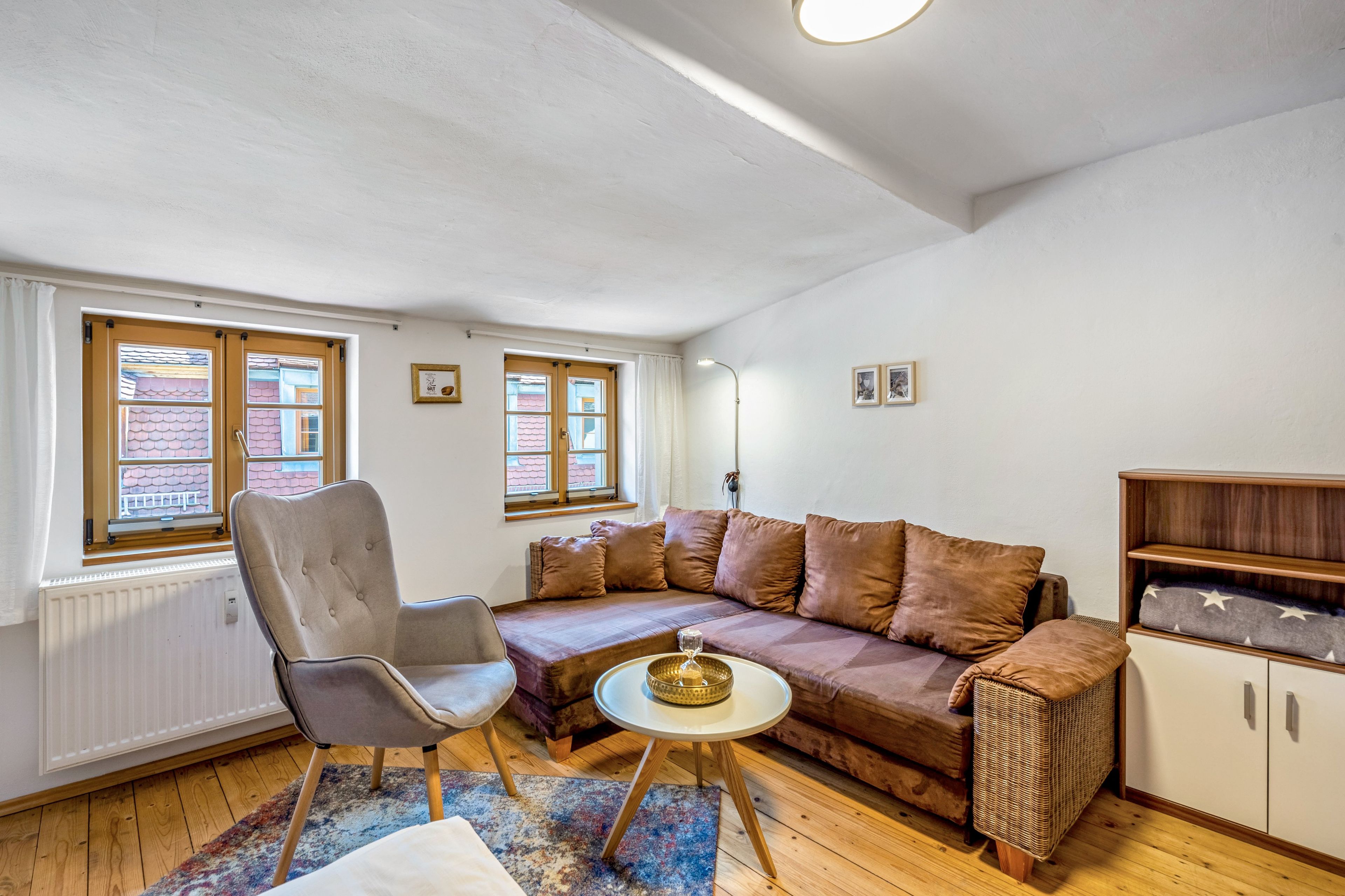 Ein gemütliches Wohnzimmer mit einer Couch, einem Sessel und einem kleinen runden Tisch.
