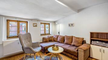 Ein gemütliches Wohnzimmer mit einer Couch, einem Sessel und einem kleinen runden Tisch.