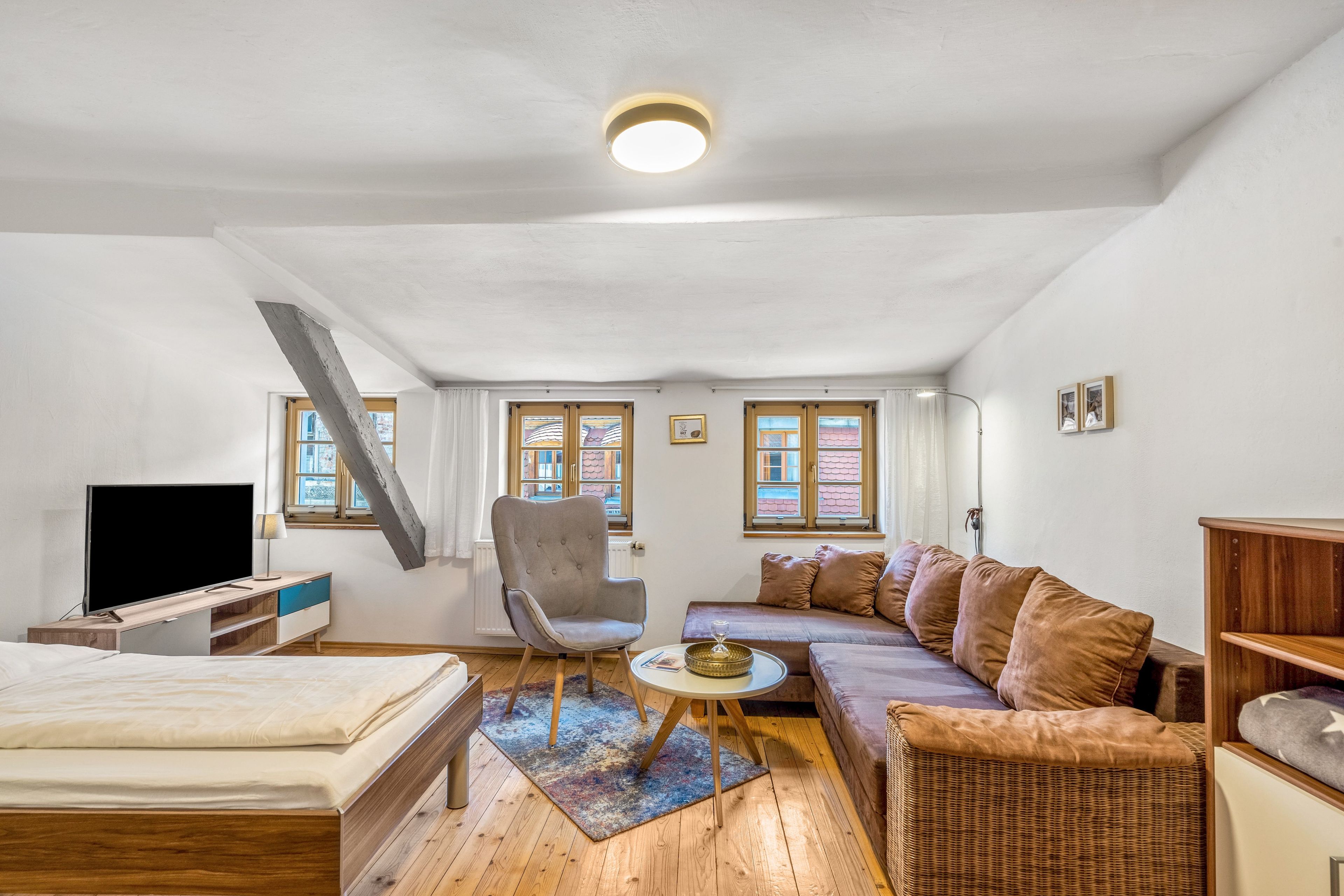 Ein modernes Wohnzimmer mit einer Couch, einem Sessel und einem Fernseher.