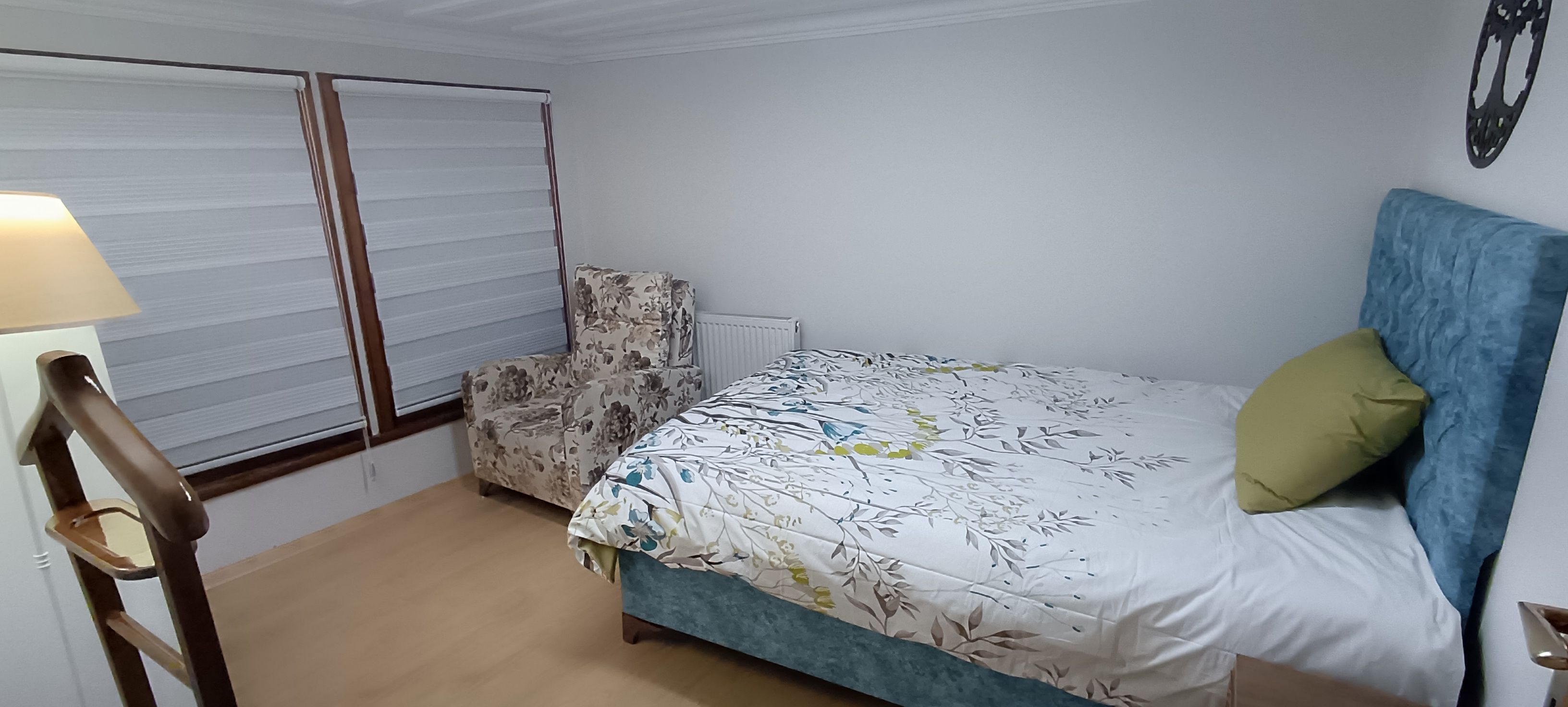 A bedroom with a bed, a chair, a lamp, and a radiator.