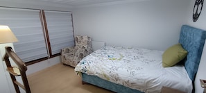 Une chambre à coucher avec un lit, une chaise, une lampe et un radiateur.