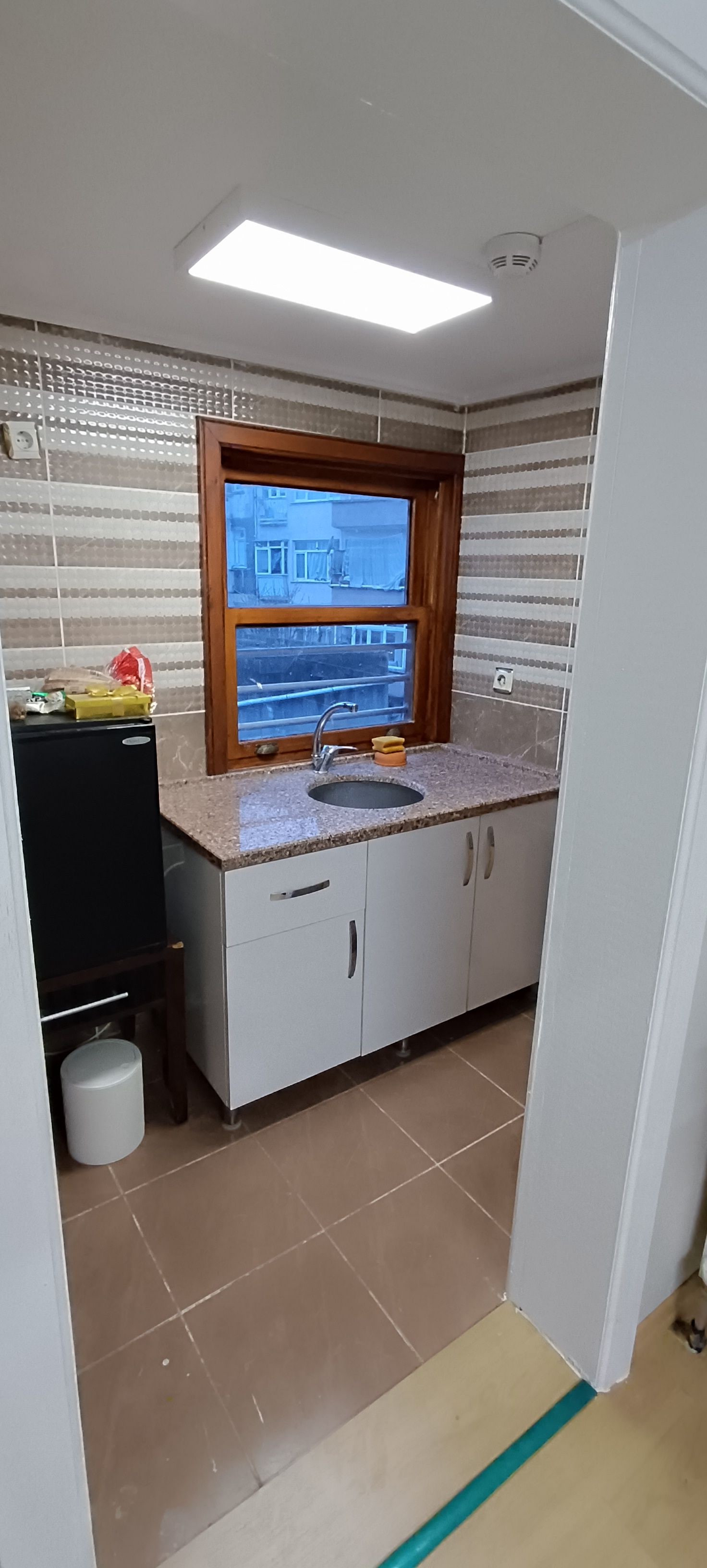 Cozinha com janela, pia, armários e geladeira.