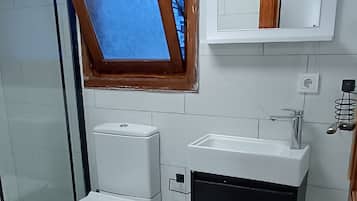 A bathroom with a toilet, sink, and a window above the sink.