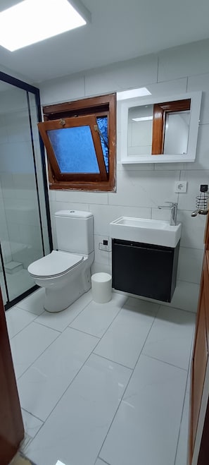 Une salle de bain avec des toilettes, un lavabo et une fenêtre située au-dessus du lavabo.