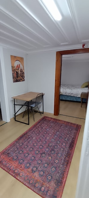 Une pièce comprenant un lit, un bureau avec une chaise, un tapis à motifs et un tableau accroché au mur.
