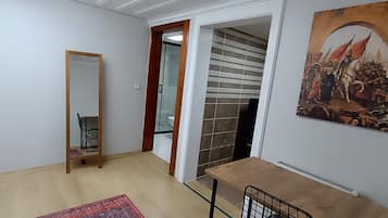 Quarto com porta de madeira, espelho, parede revestida de azulejos e um quadro.