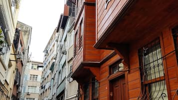 Rua estreita no centro urbano, ladeada por edifícios altos com varandas e janelas.